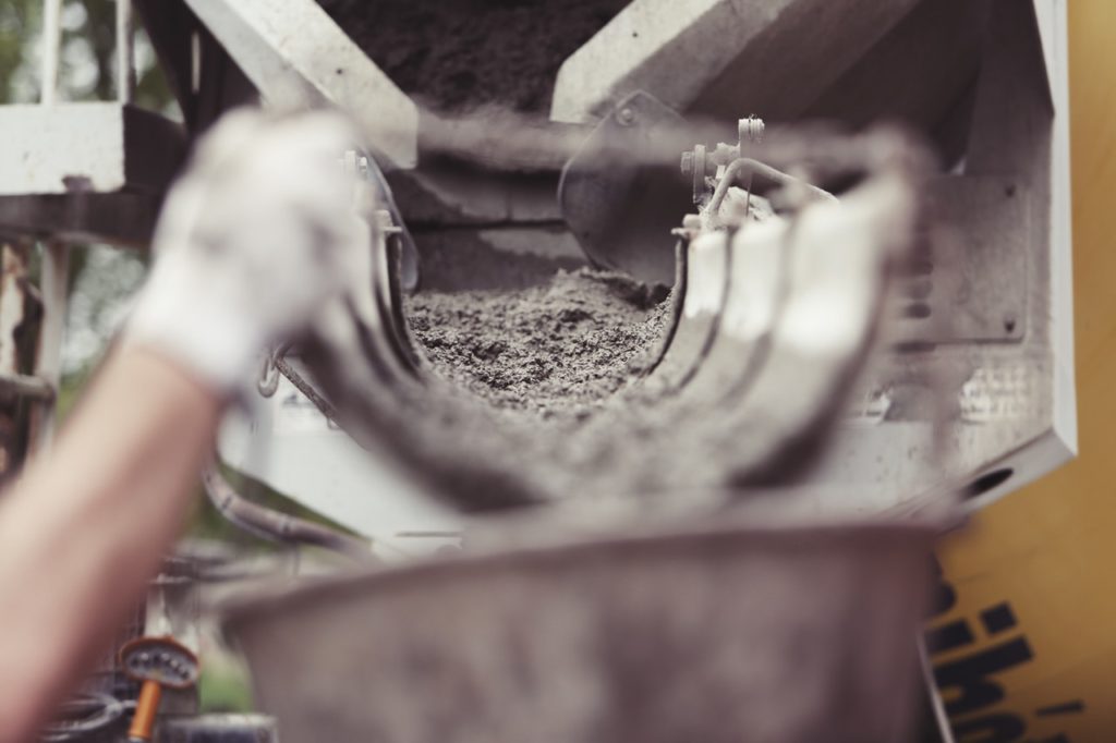 Photo showing mixer pouring concrete. Ready for the workers to disperse. Hand in photo. 
